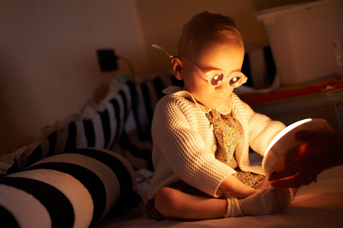 Bambina che gioca con una luce in una stanza in penombra durante una seduta di stimolazione visiva